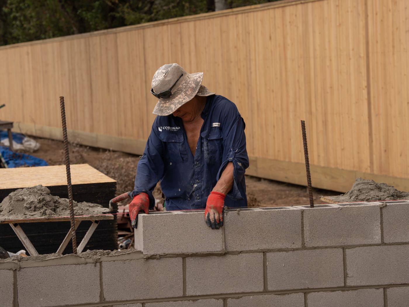 Mason laying a concrete block course for an outdoor kitchen base