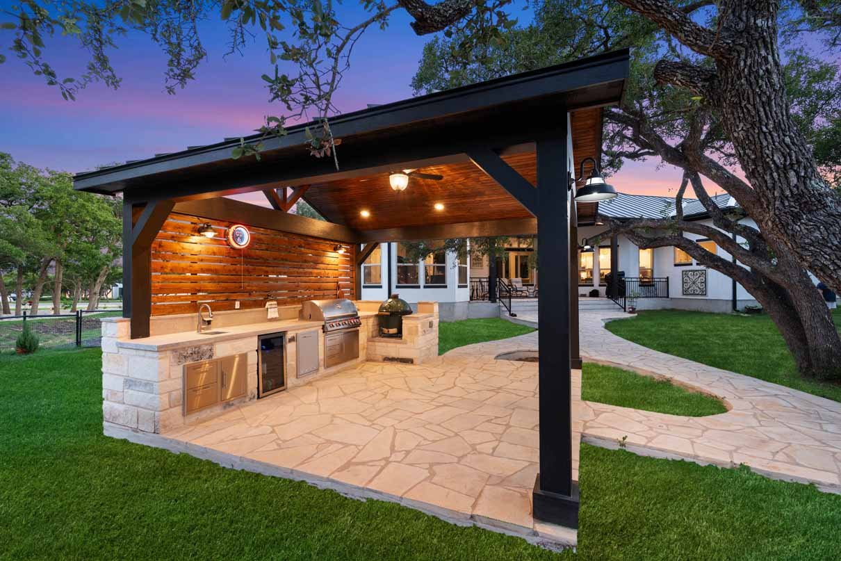 Covered patio with stone outdoor kitchen and bar by Coronado Exteriors